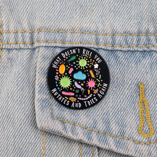 Enamel pin with quote “What Doesn’t Kill You, Mutates and Tries Again” on scrub top
